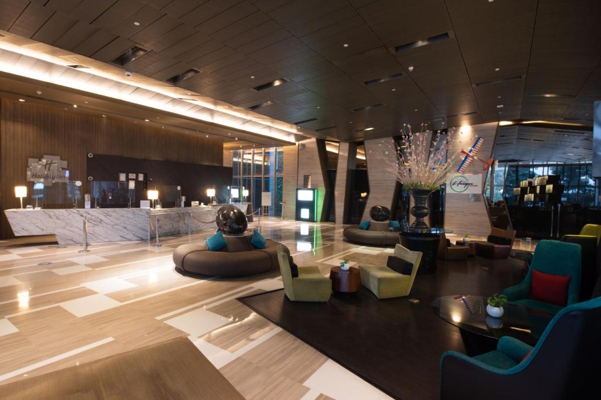 a lobby with couches and chairs in a building at Holiday Inn New Delhi Aerocity by IHG in New Delhi