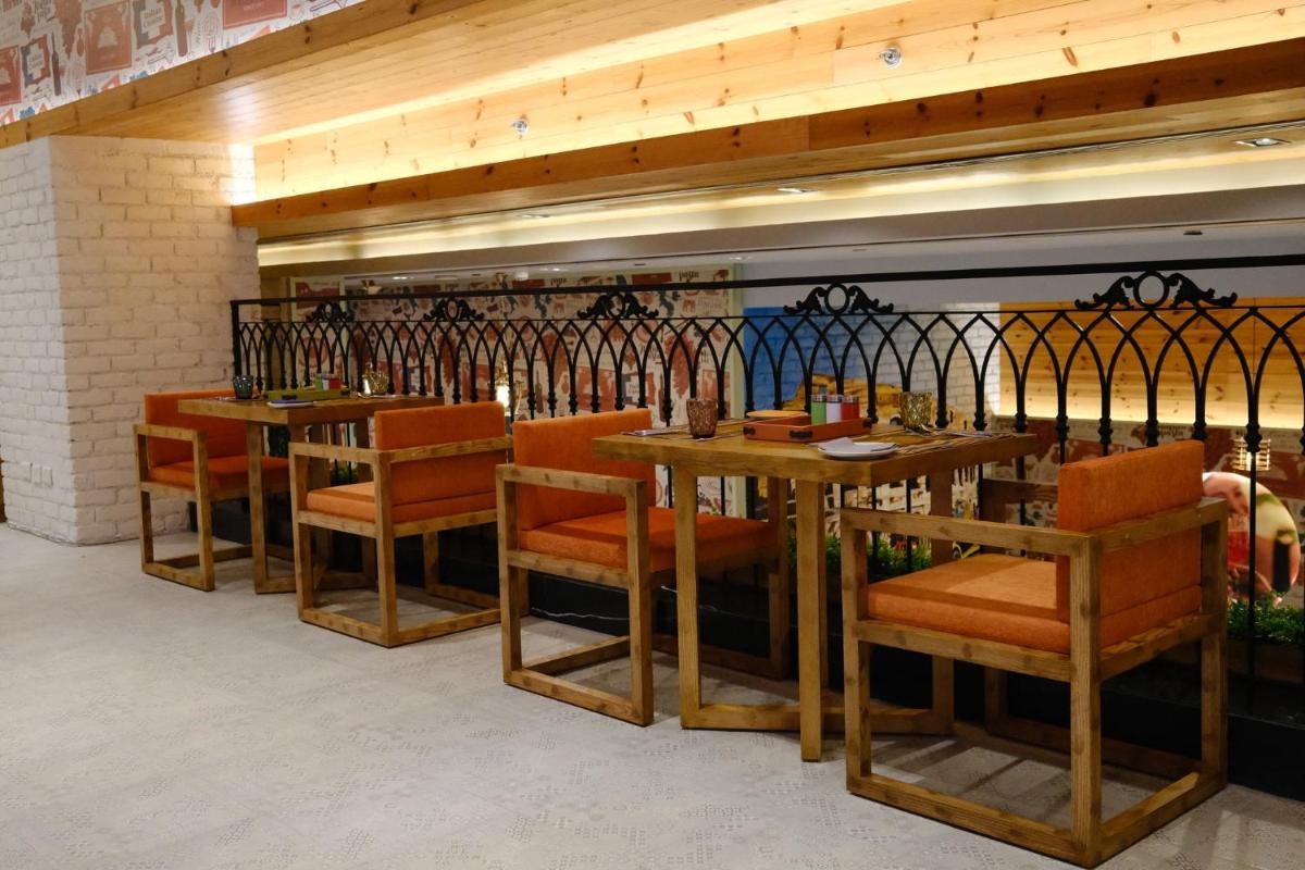 a restaurant with wooden tables and orange chairs at Holiday Inn New Delhi Aerocity by IHG in New Delhi