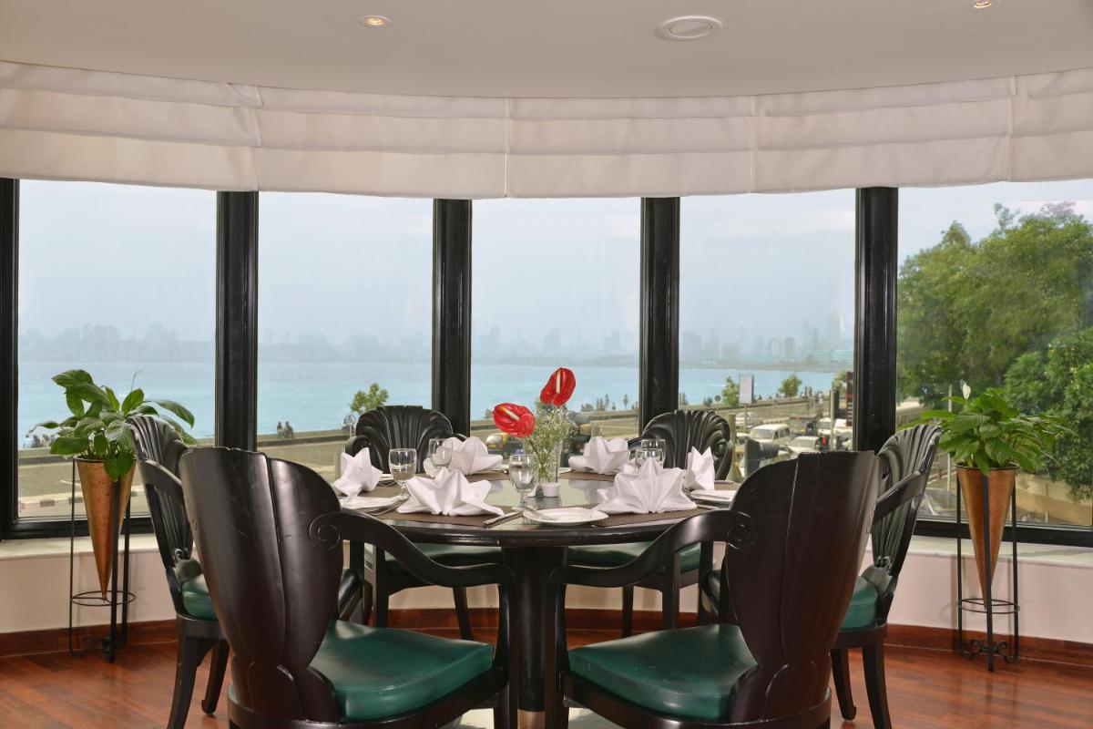 a dining room with a table and chairs and windows at Hotel Marine Plaza in Mumbai