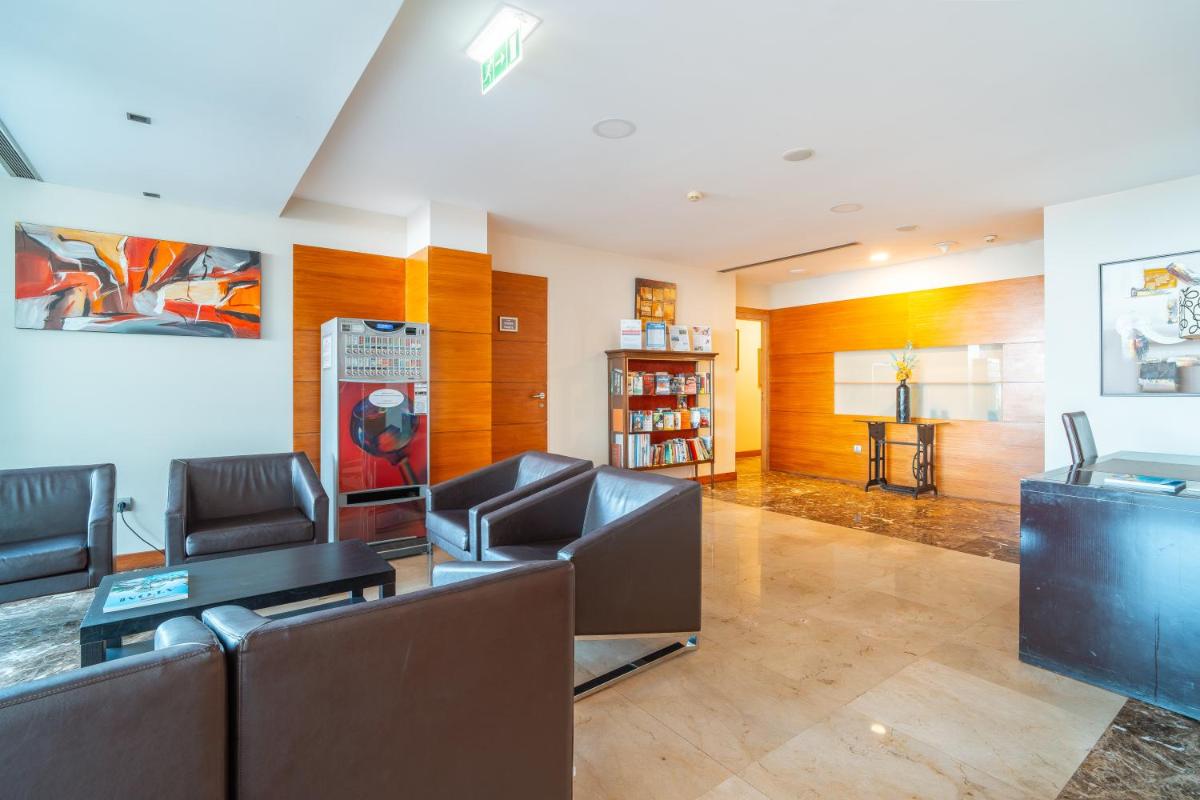 uma sala de estar com cadeiras de couro e uma mesa em Muthu Raga Madeira Hotel no Funchal