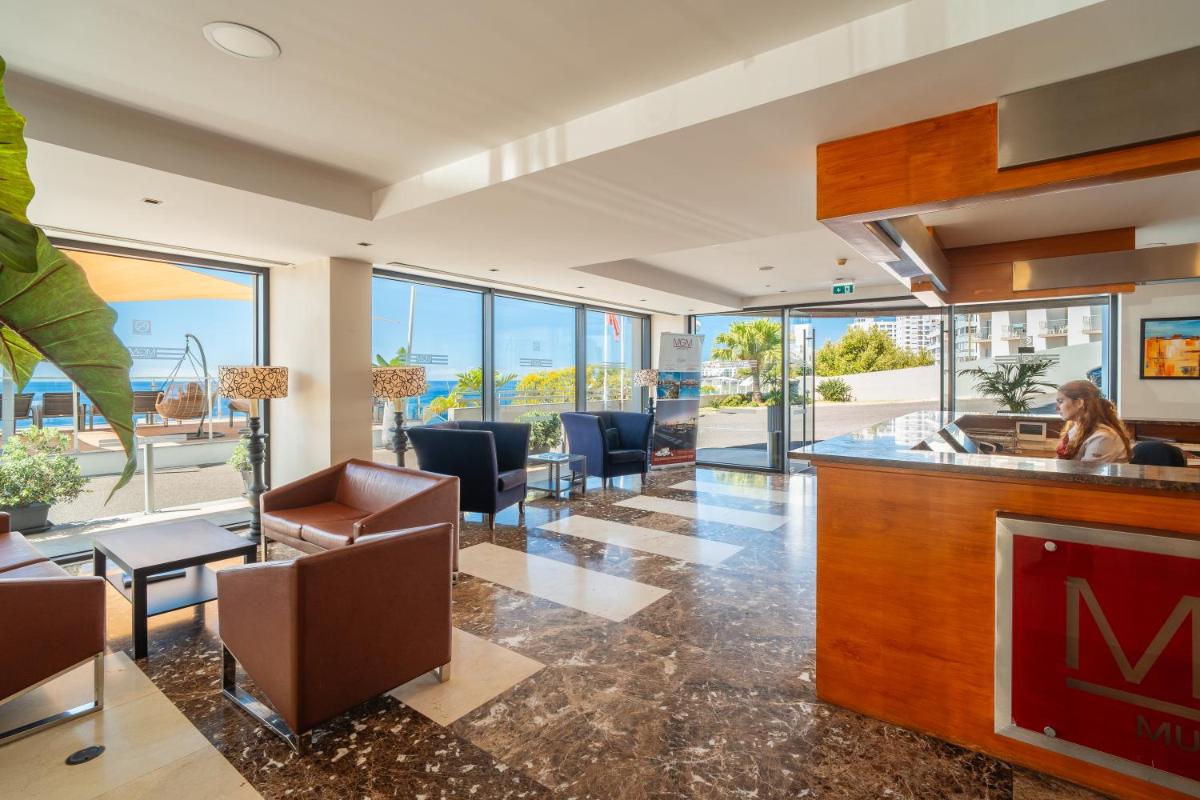 um lobby com um bar com cadeiras e mesas em Muthu Raga Madeira Hotel no Funchal