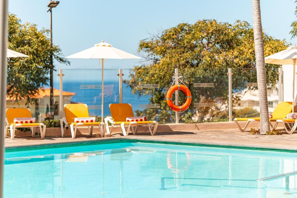 uma piscina com cadeiras e um guarda-sol em Muthu Raga Madeira Hotel no Funchal mais 71 fotografias