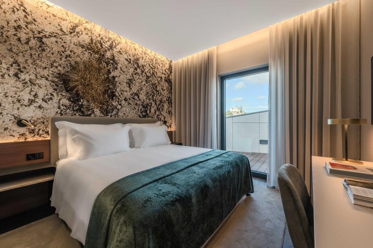 um quarto com uma cama e uma janela grande em Dolinas Climbing Hotel em Porto de Mós