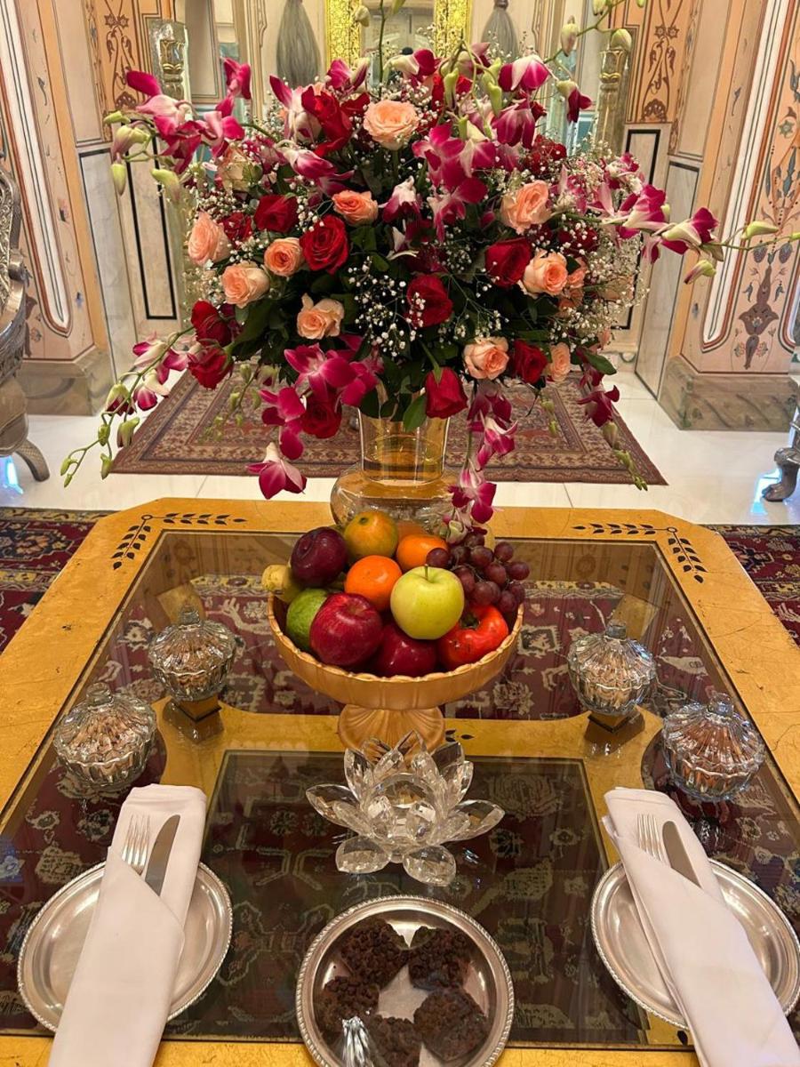 a table topped with a bowl of fruit and flowers at The Raj Palace (Small Luxury Hotels of the World) in Jaipur