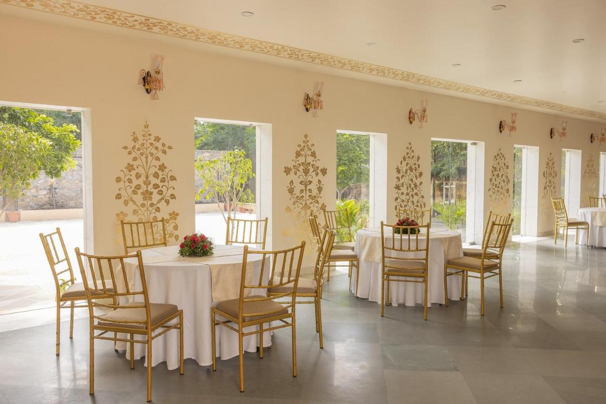 a dining room with white tables and chairs and windows at Royal Heritage Haveli - By Leisure Hotels in Jaipur