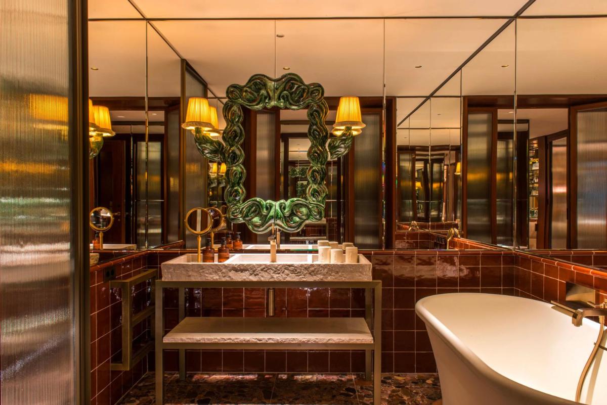 Un baño con bañera, lavabo y espejo. en Brach Madrid - Evok Collection, en Madrid