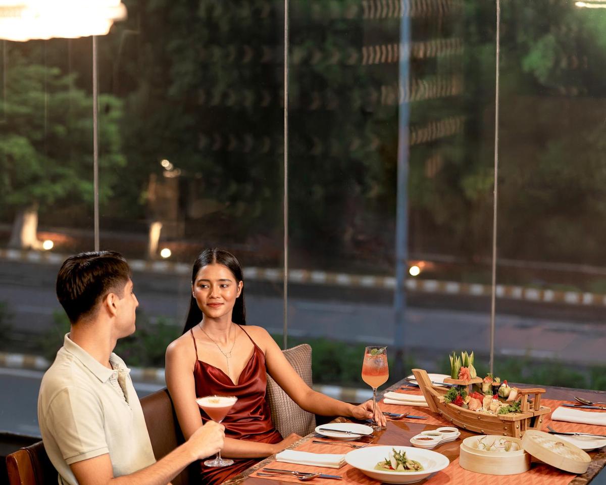 a man and woman sitting at a table with wine glasses at The Leela Ambience Gurugram Hotel & Residences - The Luxury Urban Sanctuary in Gurgaon