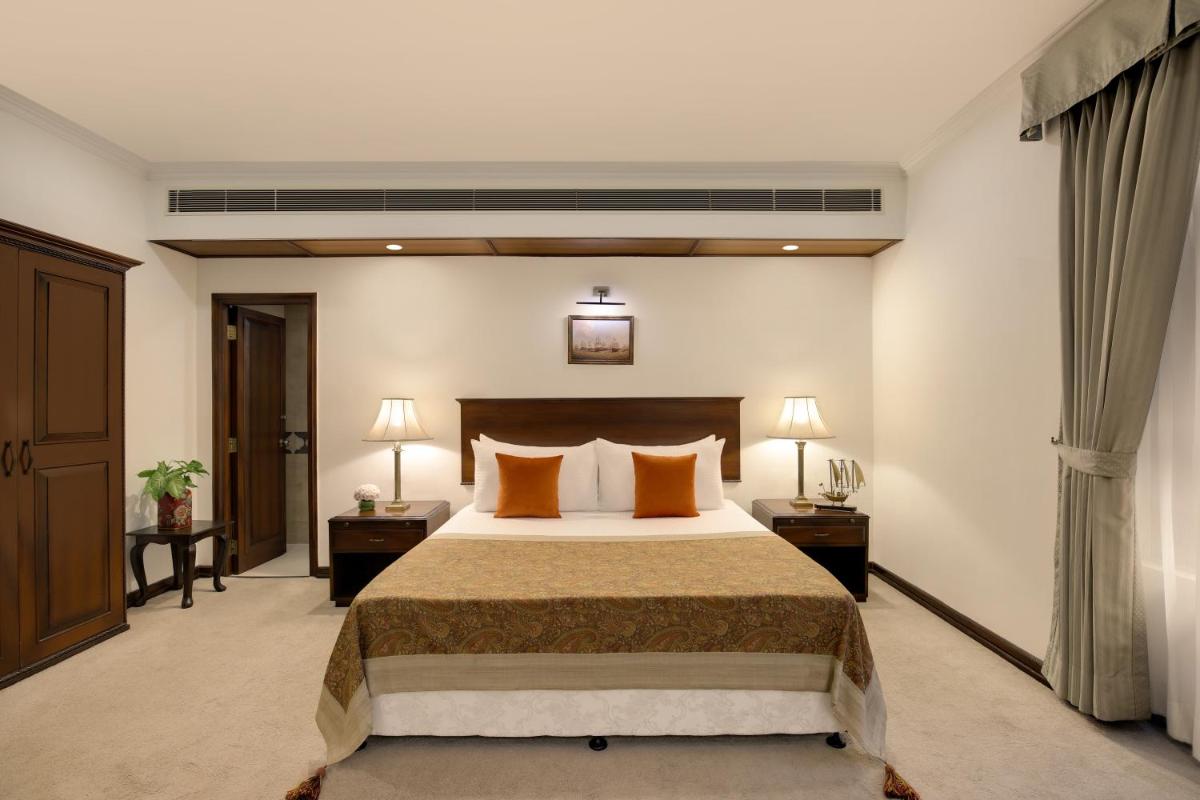 a hotel room with a bed and two nightstands and two lamps at Ambassador, New Delhi - IHCL SeleQtions in New Delhi a hotel room with a bed and two nightstands and two lamps at Ambassador, New Delhi - IHCL SeleQtions in New Delhi