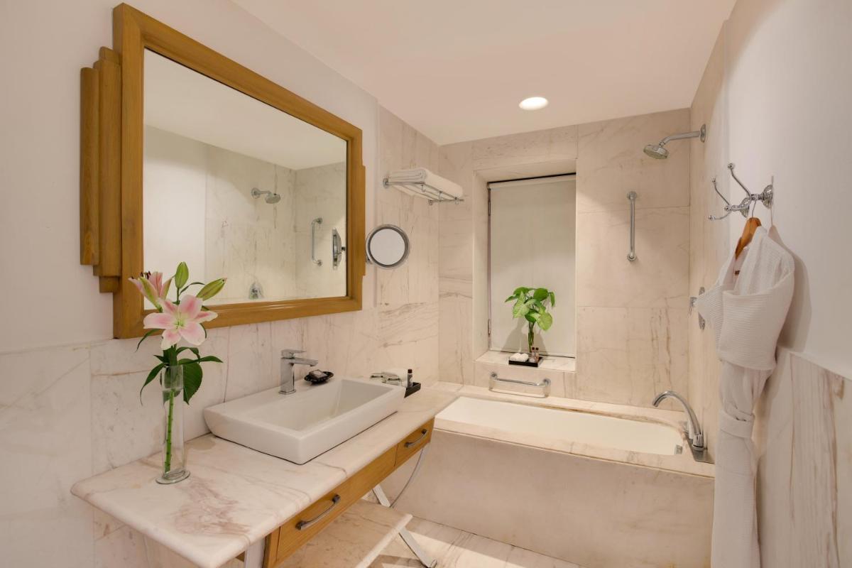 a bathroom with a sink and a tub and a mirror at Ambassador, New Delhi - IHCL SeleQtions in New Delhi a bathroom with a sink and a tub and a mirror at Ambassador, New Delhi - IHCL SeleQtions in New Delhi
