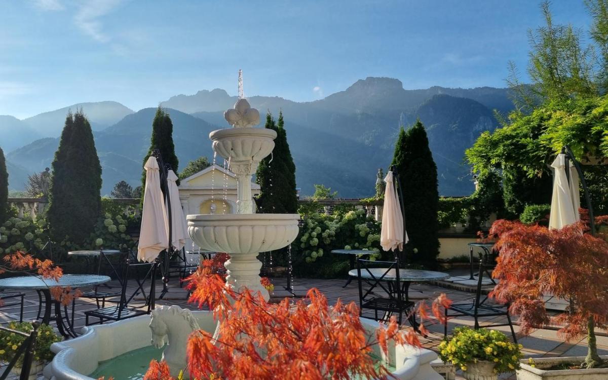 einen großen weißen Brunnen in einem Innenhof mit Tischen und Stühlen in der Unterkunft Boutique Hotel Residenz Winkler in Aschau im Chiemgau