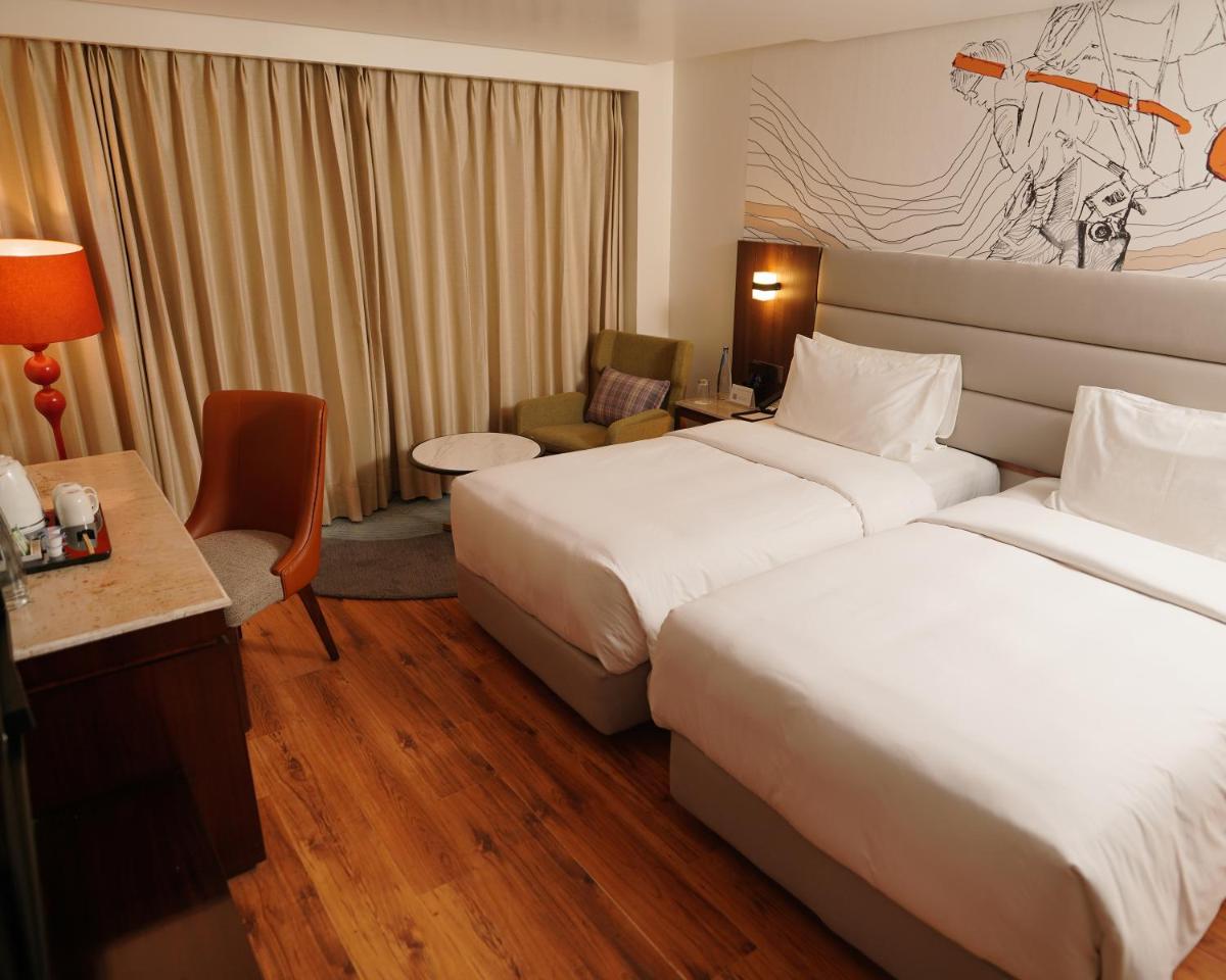 a hotel room with two beds and a desk at Hyatt Centric Rajpur Road Dehradun in Dehradun