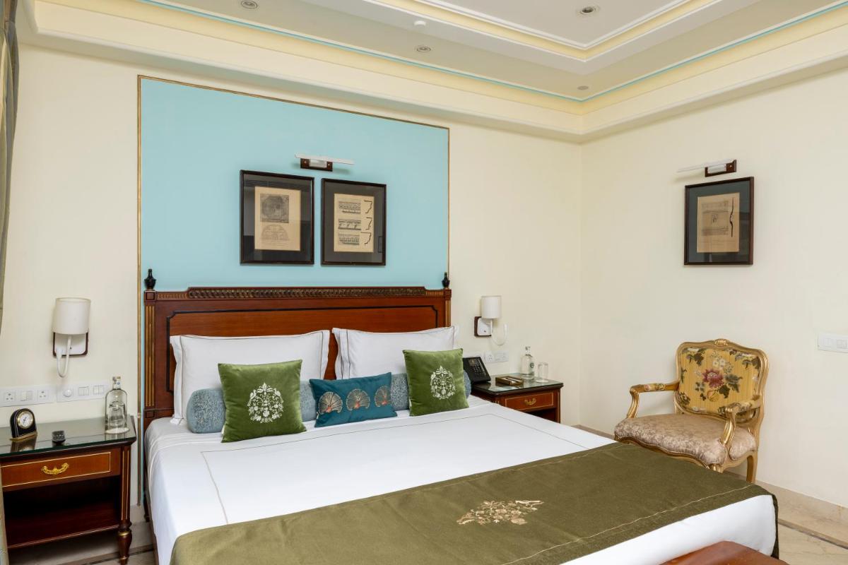 a bedroom with a large white bed and a chair at Taj Fateh Prakash Palace Udaipur in Udaipur