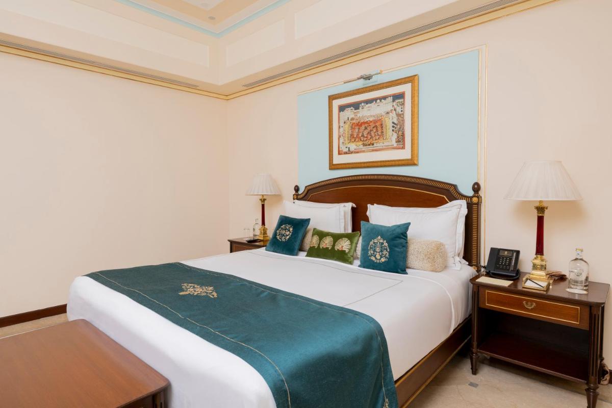 a bedroom with a large white bed with blue pillows at Taj Fateh Prakash Palace Udaipur in Udaipur
