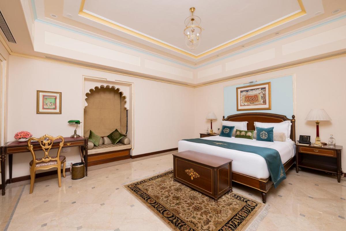 a bedroom with a bed and a desk and a mirror at Taj Fateh Prakash Palace Udaipur in Udaipur