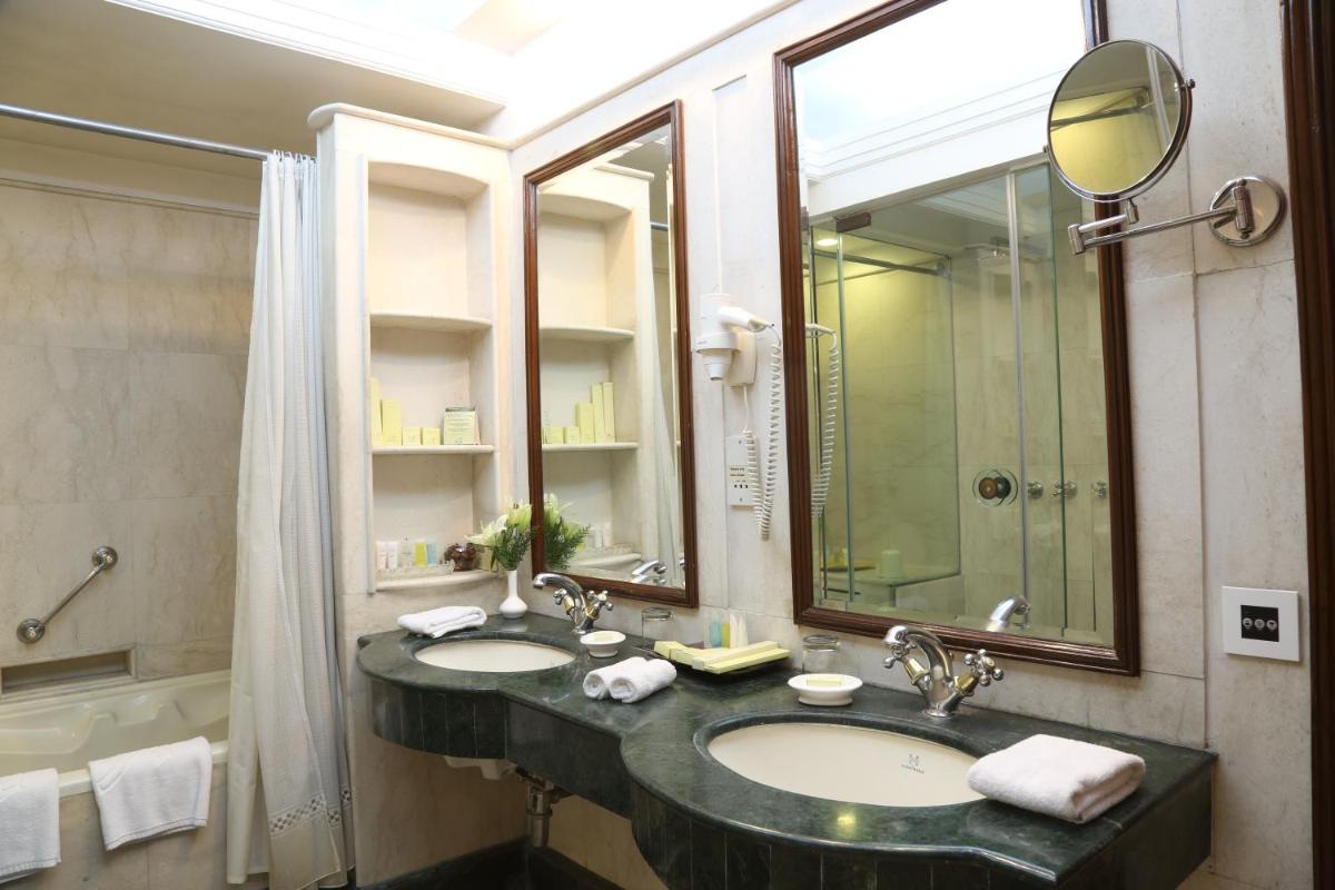 a bathroom with two sinks and a shower and a mirror at The Ashok, New Delhi in New Delhi a bathroom with two sinks and a shower and a mirror at The Ashok, New Delhi in New Delhi