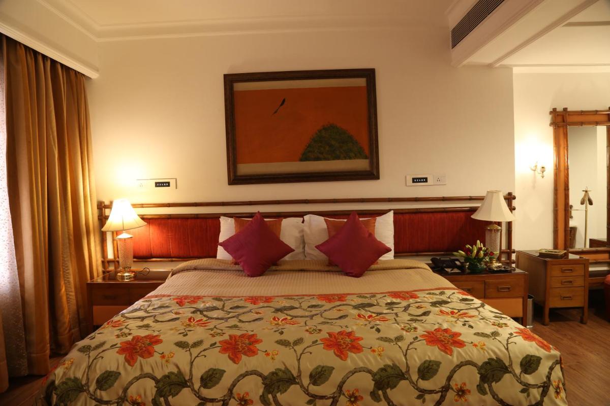 a hotel room with a bed with red pillows at The Ashok, New Delhi in New Delhi a hotel room with a bed with red pillows at The Ashok, New Delhi in New Delhi