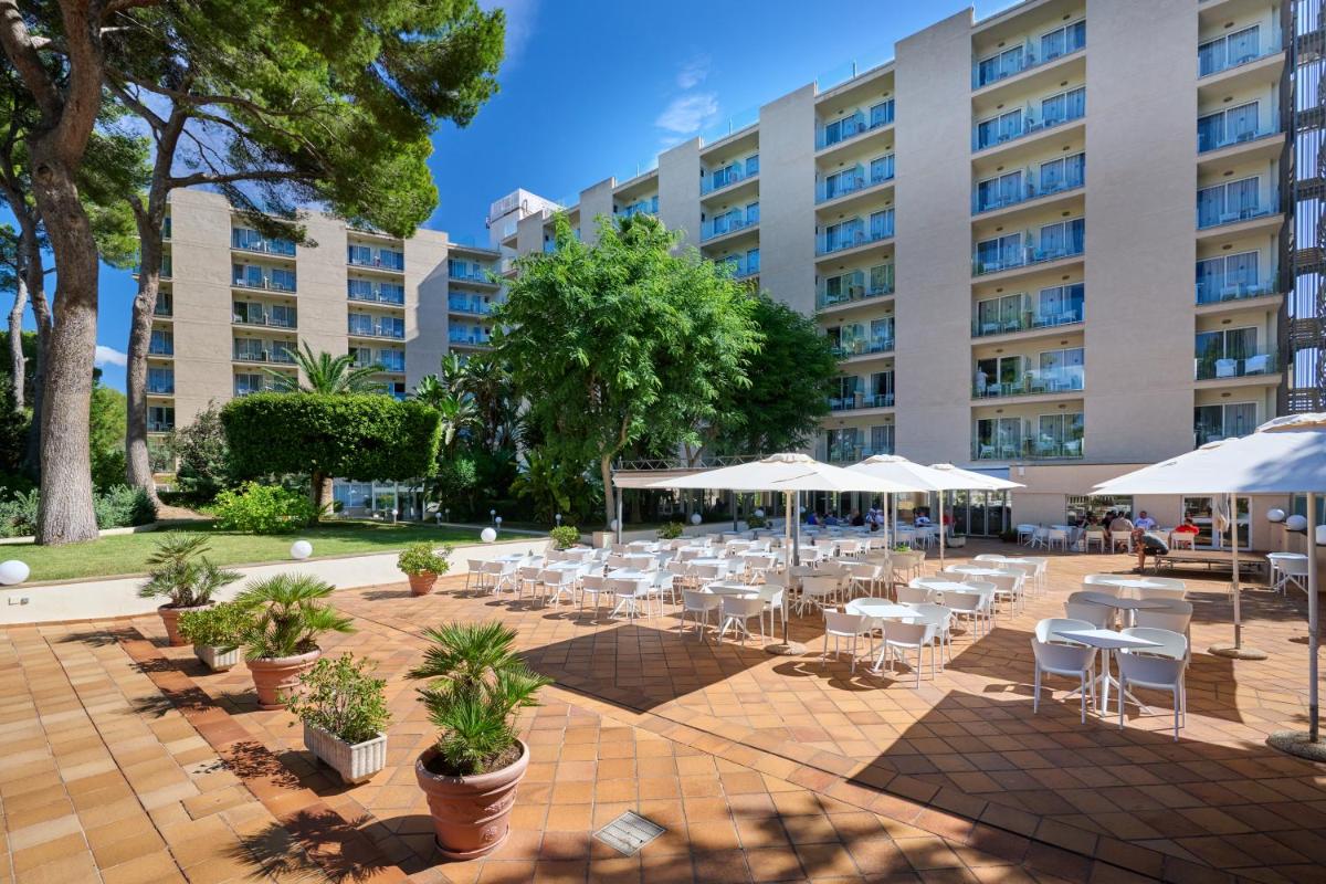 un gran edificio con mesas, sillas y sombrillas en Grupotel Orient, en Playa de Palma