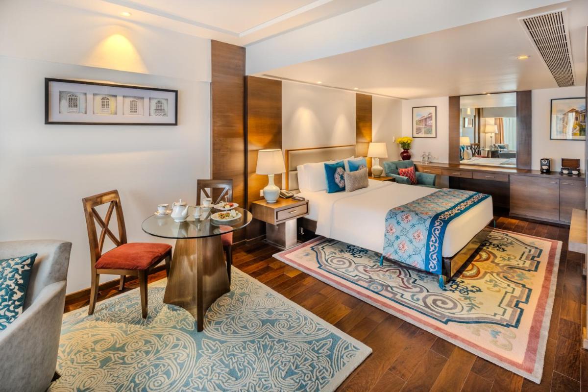 a bedroom with a bed and a desk and a table at Vivanta Goa, Panaji in Panaji a bedroom with a bed and a desk and a table at Vivanta Goa, Panaji in Panaji