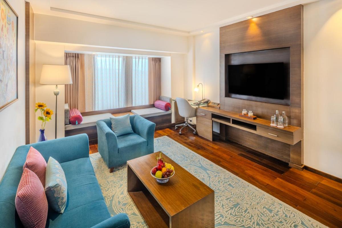 a living room with a blue couch and a television at Vivanta Goa, Panaji in Panaji a living room with a blue couch and a television at Vivanta Goa, Panaji in Panaji