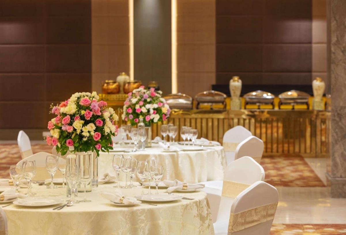 a table with white tables and chairs with flowers on it at DoubleTree By Hilton Jaipur Amer in Jaipur