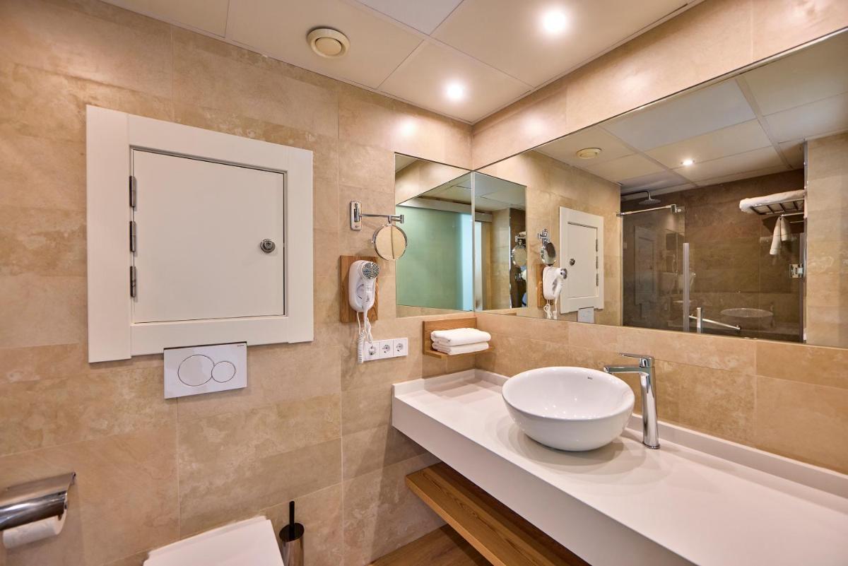 Un baño con lavabo y un espejo grande. en Aparthotel Ponent Mar, en Palmanova