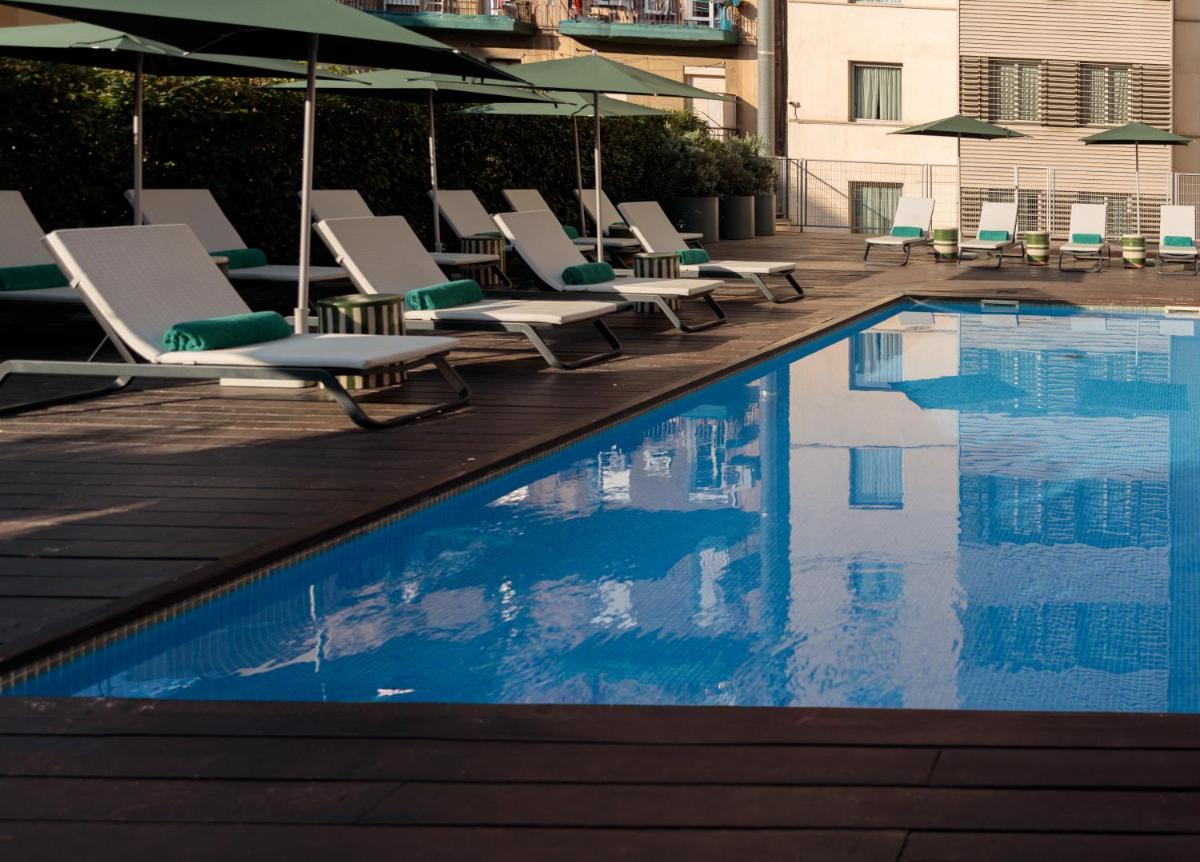 una piscina con tumbonas y sombrillas en Acevi Villarroel, en Barcelona