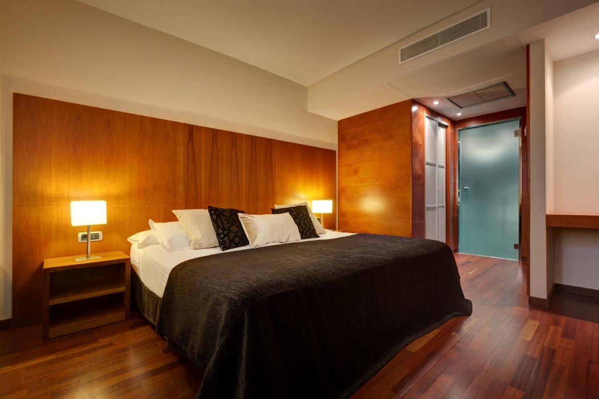 Un dormitorio con una cama grande con paredes de madera. en Acevi Villarroel, en Barcelona