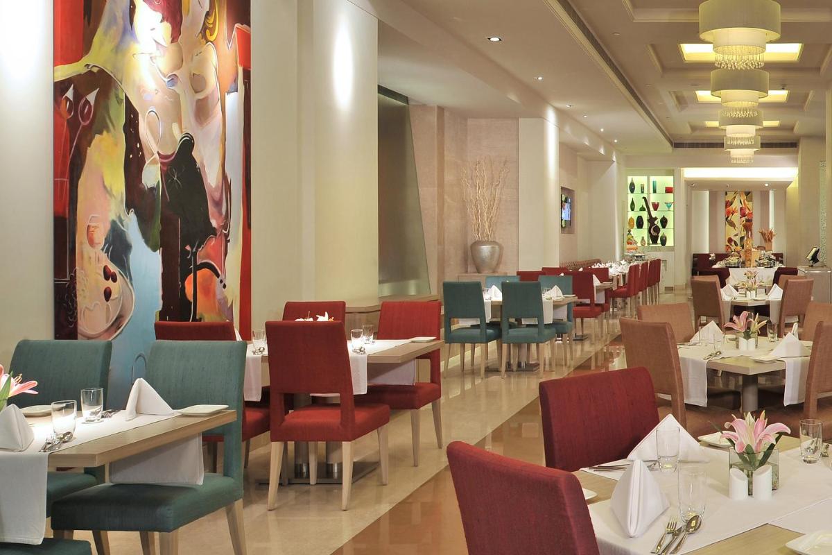 a dining room with tables and chairs in a restaurant at Radisson Hyderabad Hitec City in Hyderabad