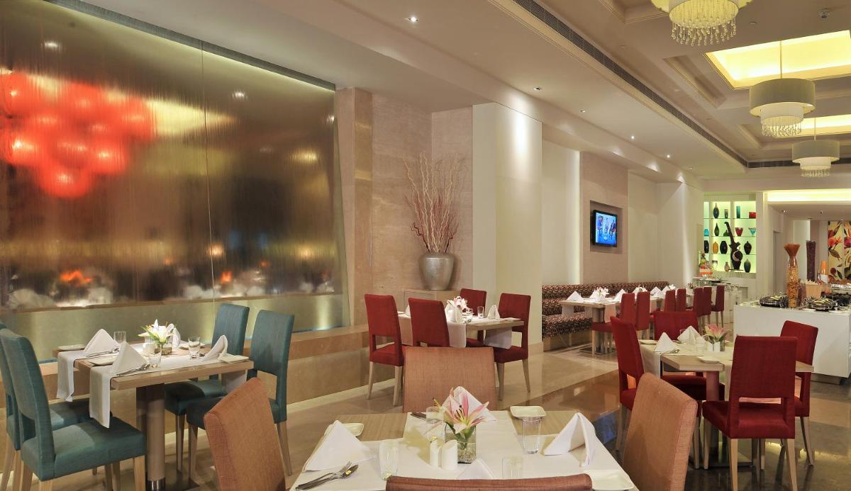 a restaurant with tables and chairs and a dining room at Radisson Hyderabad Hitec City in Hyderabad