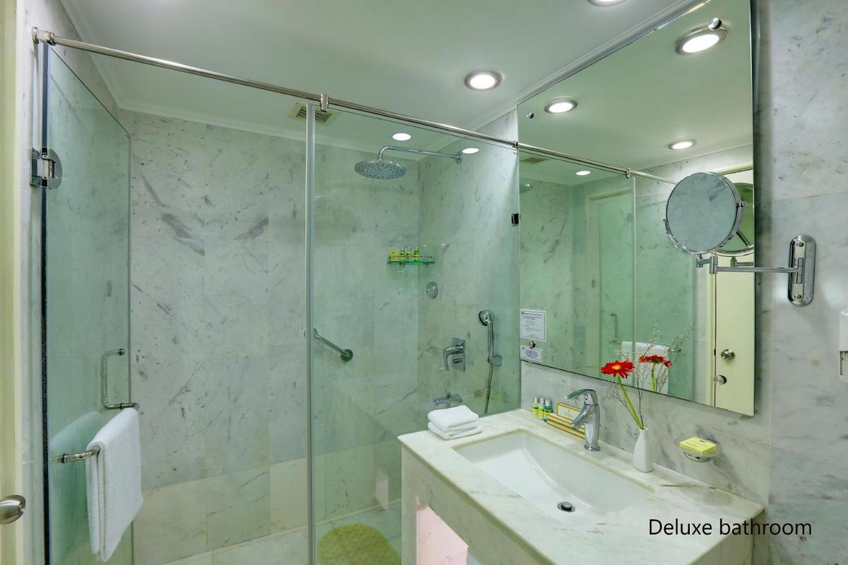 a bathroom with a shower and a sink and a mirror at Hotel Clarks Shiraz in Agra