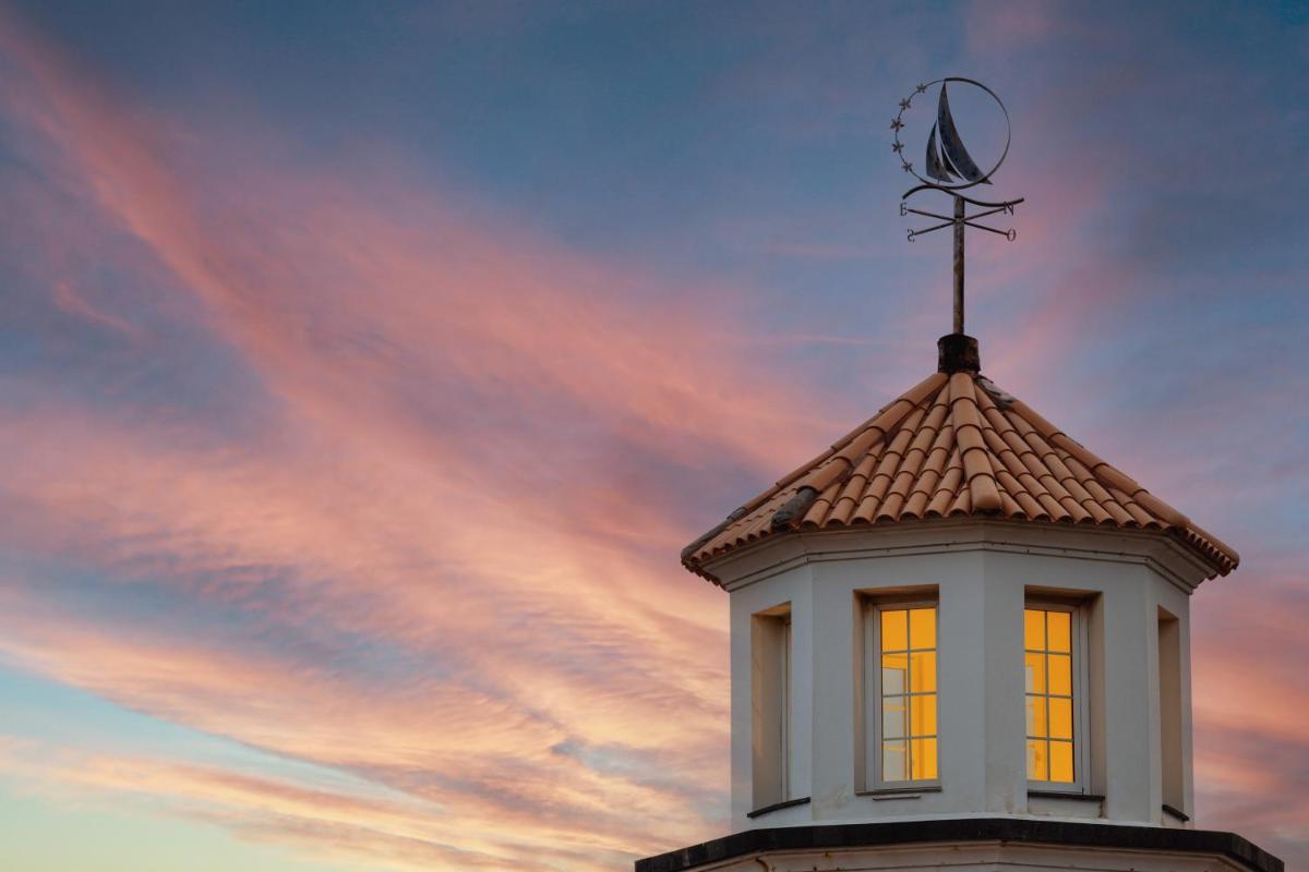 uma torre do relógio com um cata-vento em cima em Dreams Madeira Resort Spa & Marina no Caniçal uma torre do relógio com um cata-vento em cima em Dreams Madeira Resort Spa & Marina no Caniçal