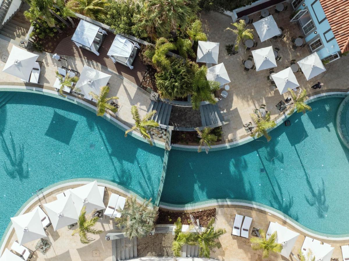 uma vista superior de uma piscina com guarda-sóis brancos em Dreams Madeira Resort Spa & Marina no Caniçal mais 291 fotografias