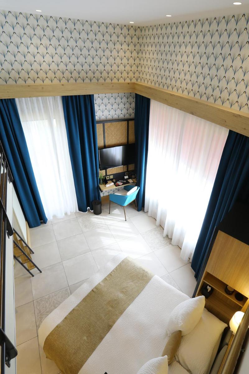 - une chambre avec des rideaux bleus, un lit et un canapé dans l'établissement Splendid Hôtel & Spa, à Bandol