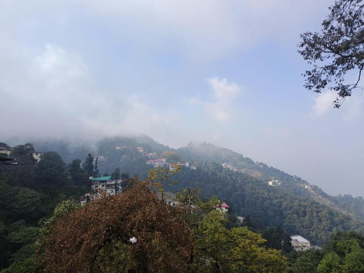 a misty mountain with a town on top of it at Perfectstayz Premium Westend at Mall Road in Mussoorie