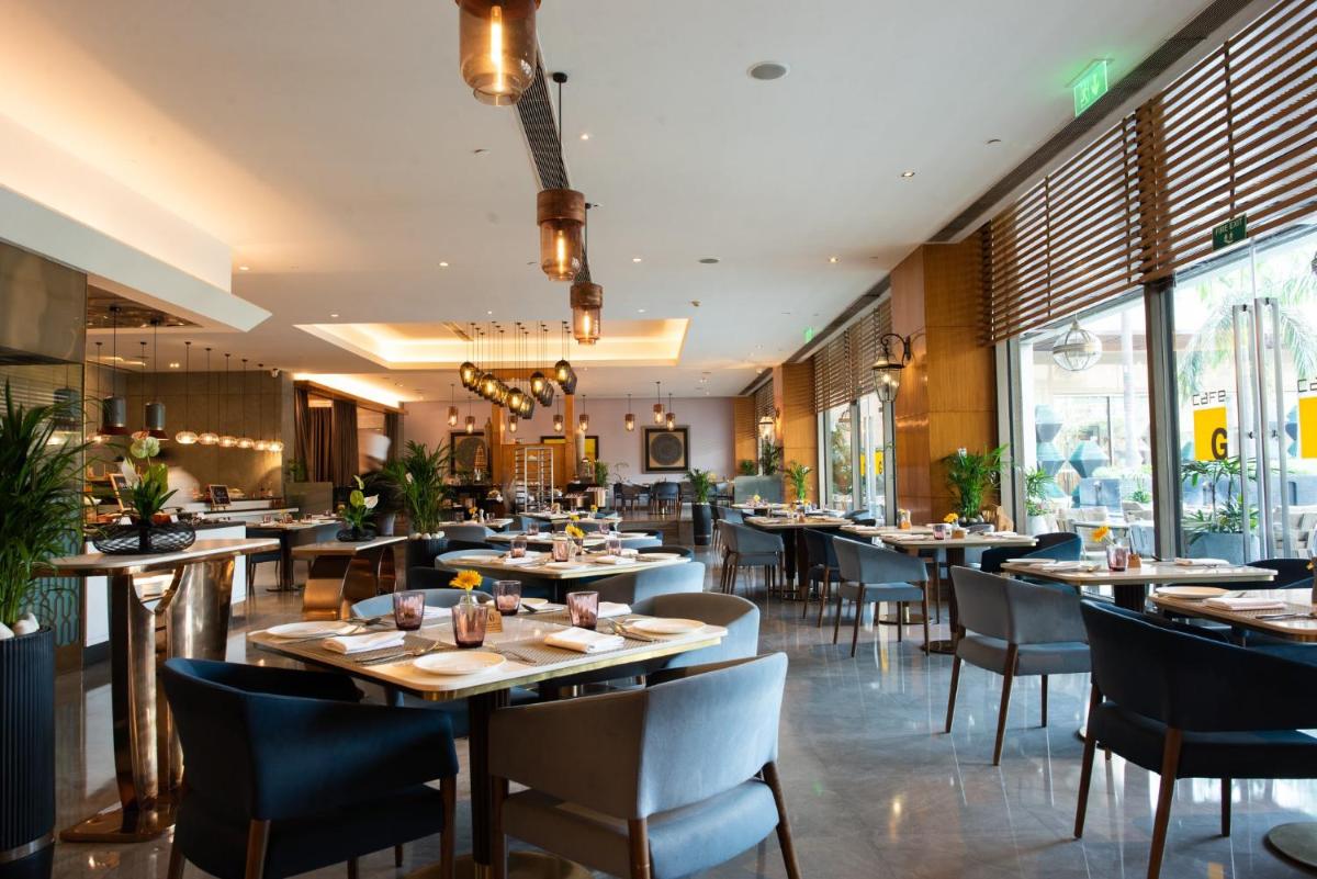 a restaurant with tables and chairs and windows at Crowne Plaza Today Gurugram by IHG in Gurgaon