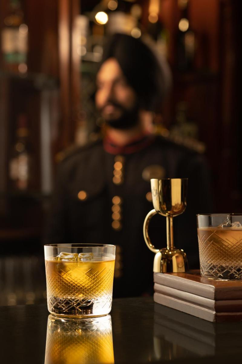 a man sitting at a bar with two glasses of whiskey at The Imperial, New Delhi in New Delhi a man sitting at a bar with two glasses of whiskey at The Imperial, New Delhi in New Delhi