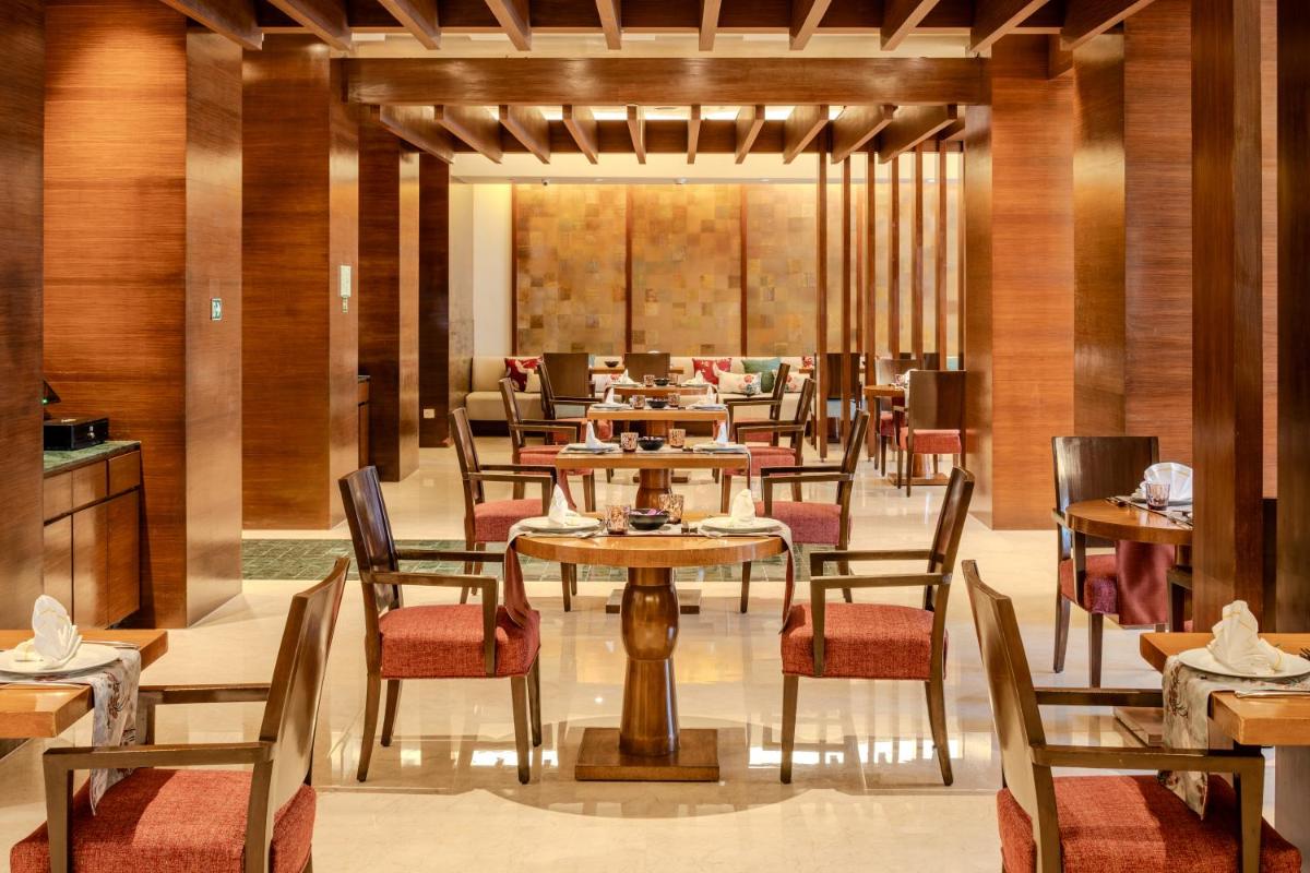 a restaurant with tables and chairs in a room at Vivanta Goa, Panaji in Panaji a restaurant with tables and chairs in a room at Vivanta Goa, Panaji in Panaji