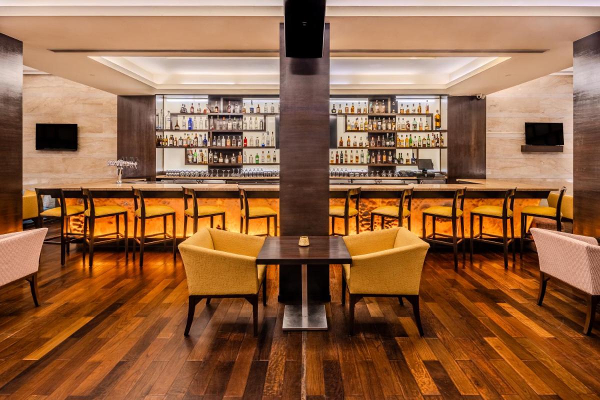 a bar in a restaurant with a table and chairs at Vivanta Goa, Panaji in Panaji a bar in a restaurant with a table and chairs at Vivanta Goa, Panaji in Panaji