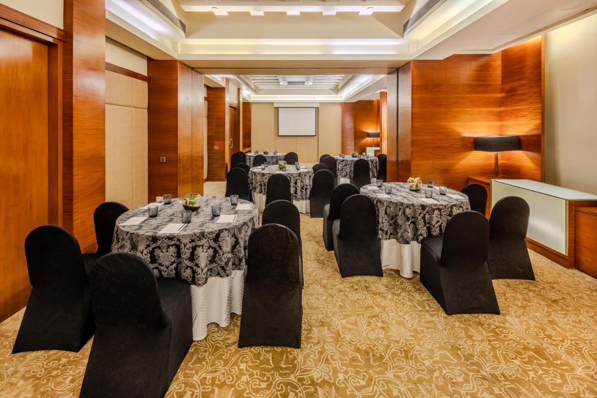 a conference room with tables and chairs and a podium at Vivanta Goa, Panaji in Panaji a conference room with tables and chairs and a podium at Vivanta Goa, Panaji in Panaji