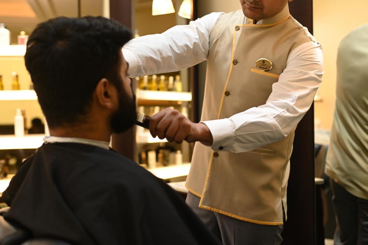 a man cutting another mans hair in a barber shop at The Imperial, New Delhi in New Delhi a man cutting another mans hair in a barber shop at The Imperial, New Delhi in New Delhi