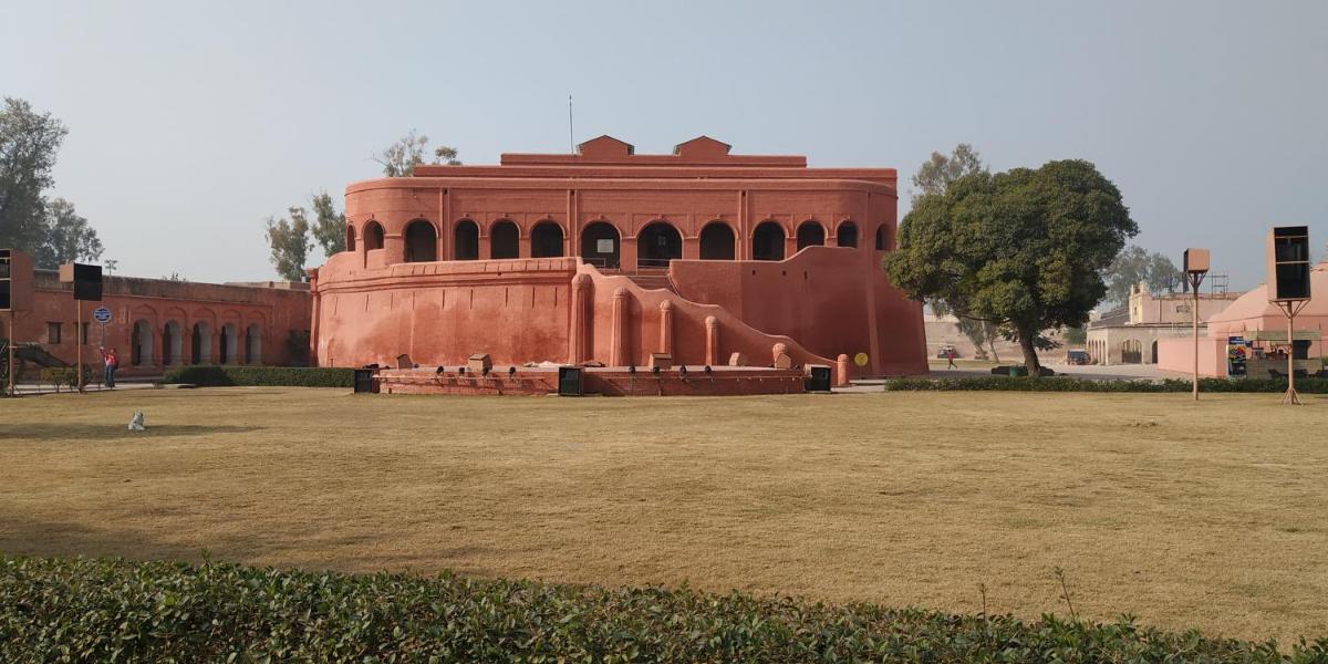 a red brick building with a large field in front at Courtyard by Marriott Amritsar in Amritsar