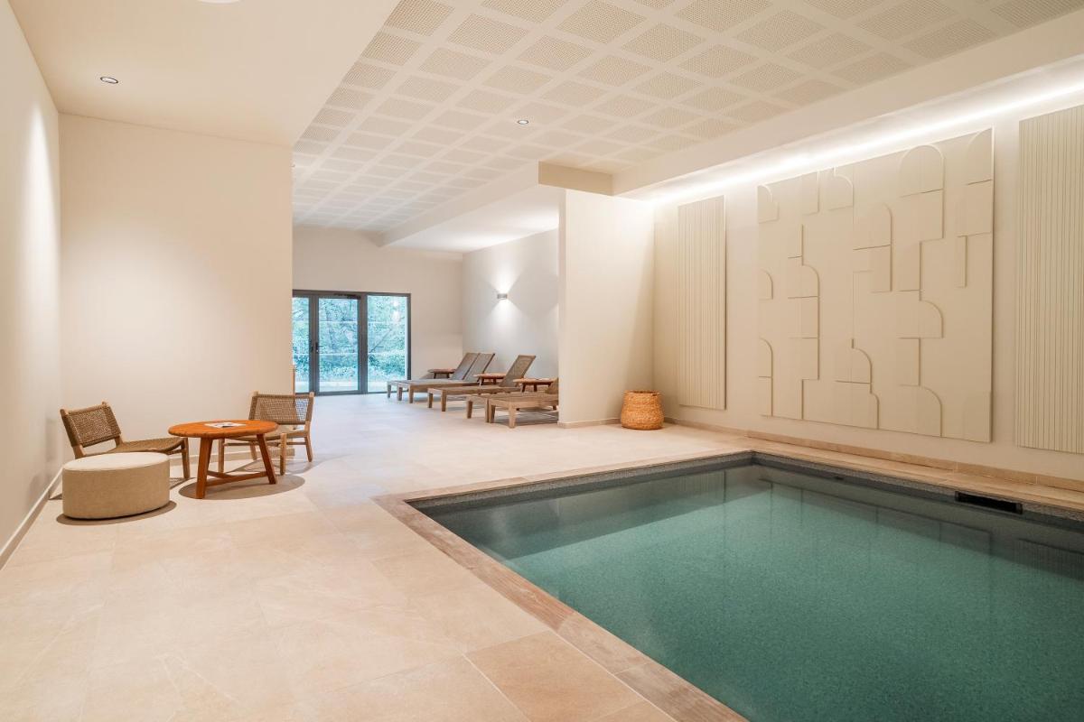 une piscine dans une pièce avec une table et des chaises dans l'établissement Setclub Hôtel & Spa Aix-en-Provence, à Aix-en-Provence