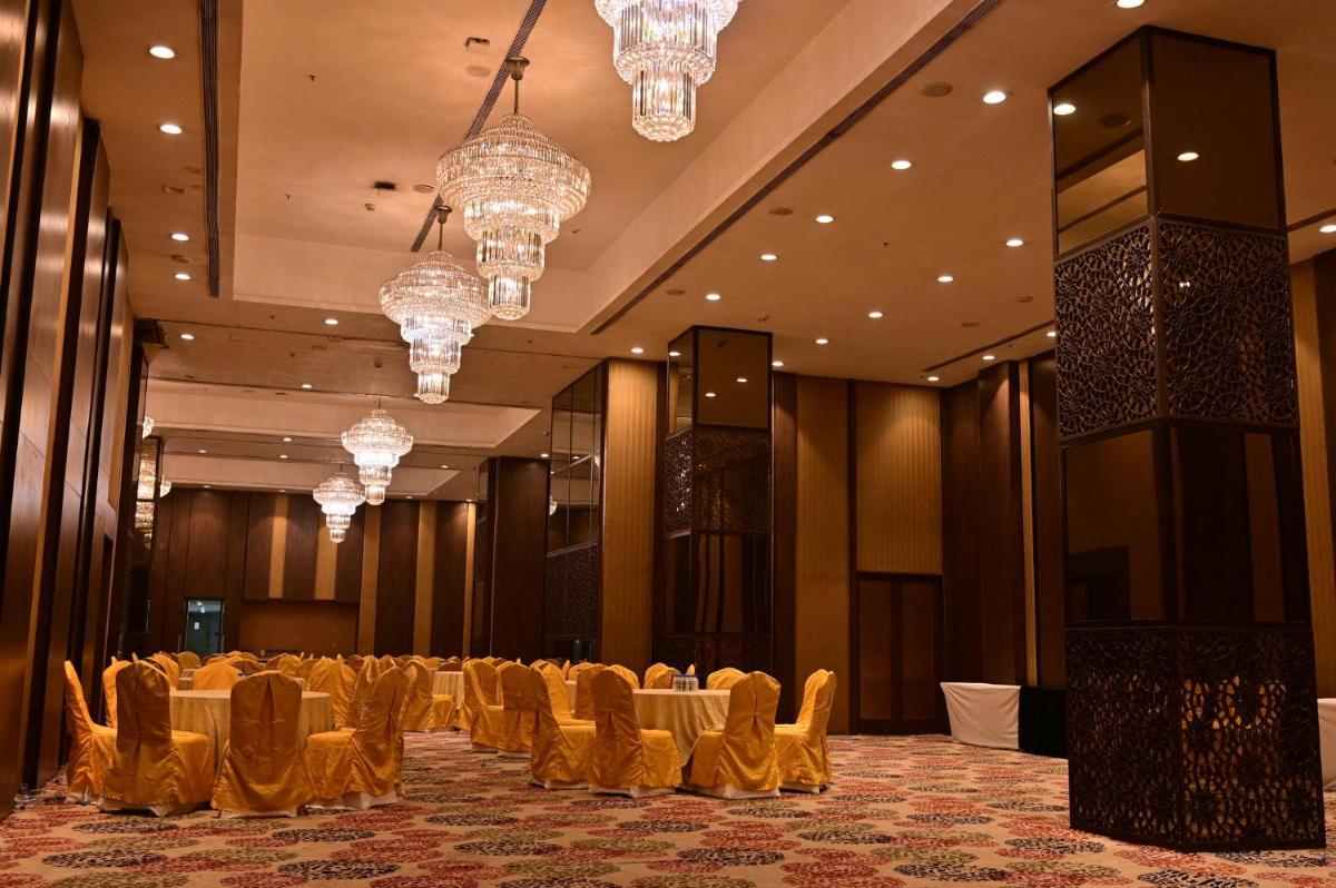 a banquet hall with tables and chandeliers at Holiday Inn Kolkata Airport by IHG in Kolkata
