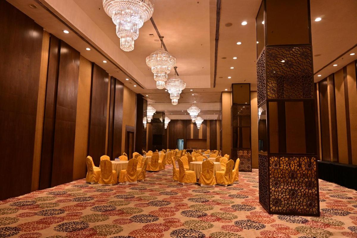 a banquet hall with chairs and tables and chandeliers at Holiday Inn Kolkata Airport by IHG in Kolkata