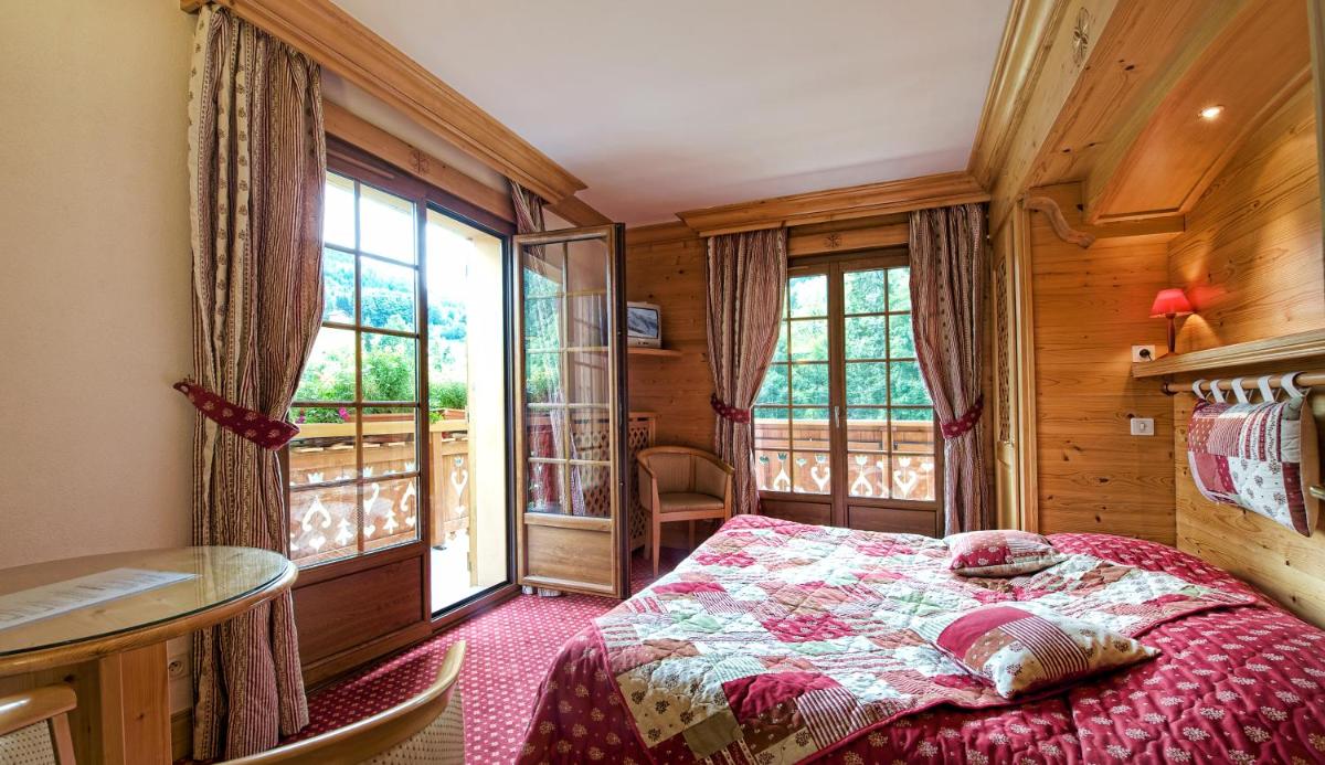 une chambre avec un lit dans une pièce avec des fenêtres dans l'établissement Hotel les Sapins, à La Clusaz