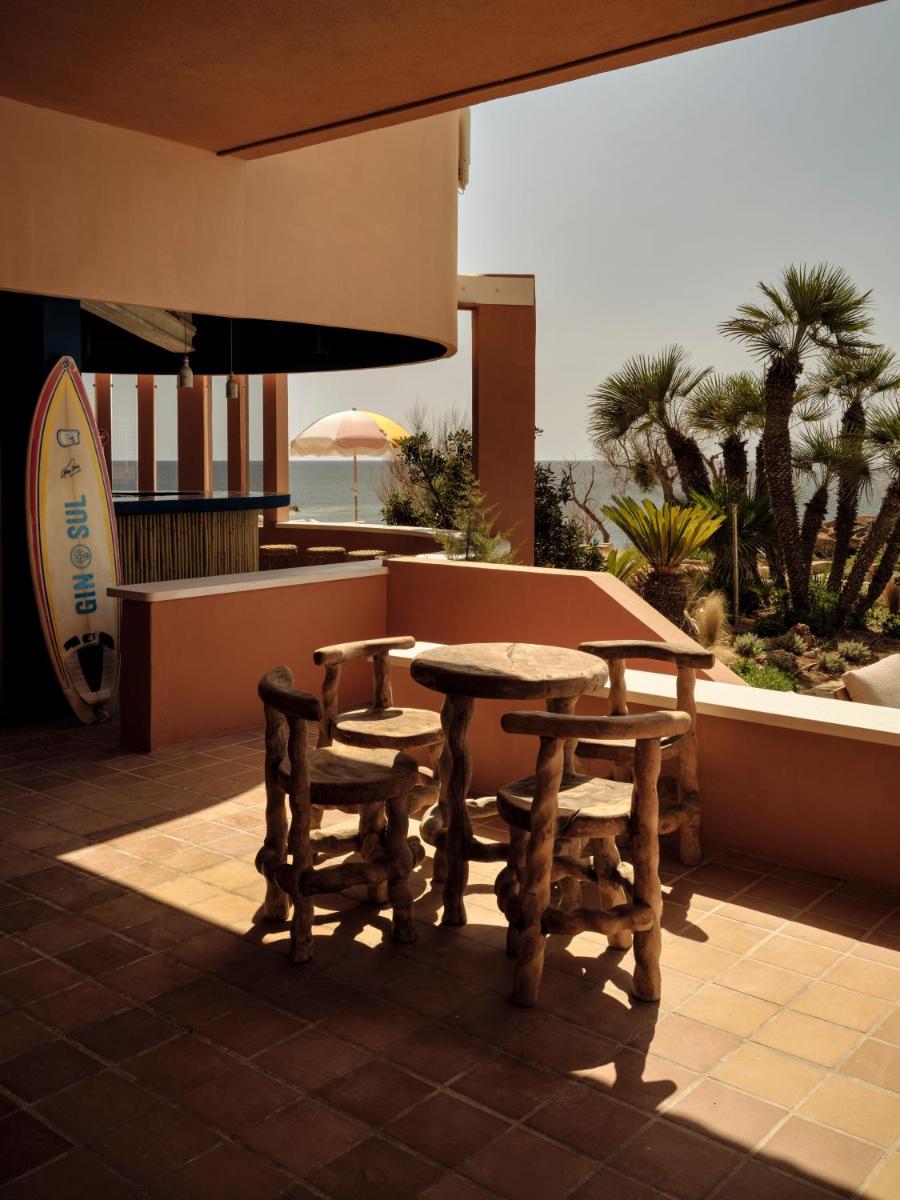 Un patio con mesa y sillas y el mar. en Bikini Island & Mountain Hotel Es Trenc -Adults only-, en Colonia de Sant Jordi