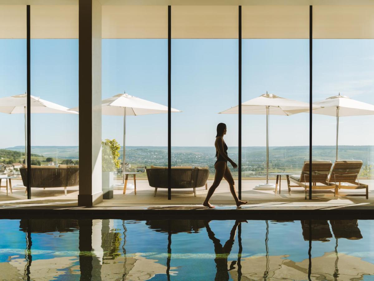 une femme qui marche au bord d'une piscine dans un bâtiment dans l'établissement Royal Champagne Hotel & Spa, à Champillon