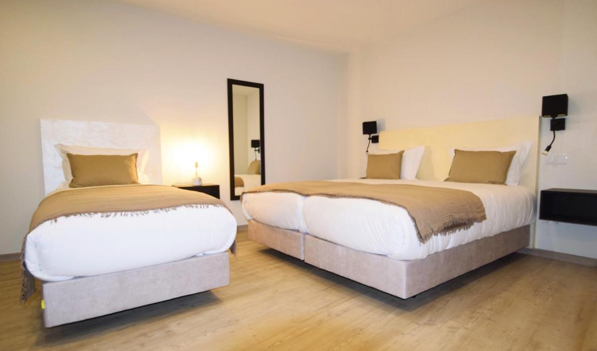 um quarto com duas camas e um espelho grande em SIENNA Hotel em Rio Maior