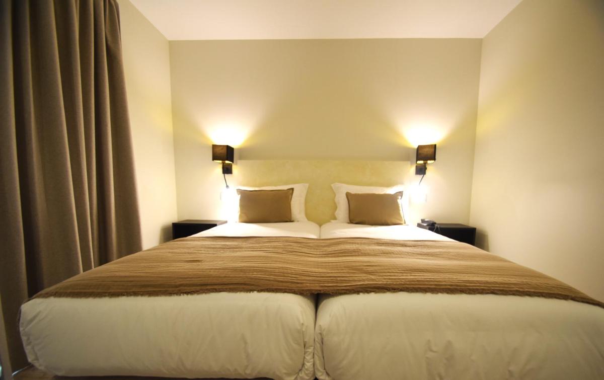 um quarto com uma cama grande com dois travesseiros em SIENNA Hotel em Rio Maior