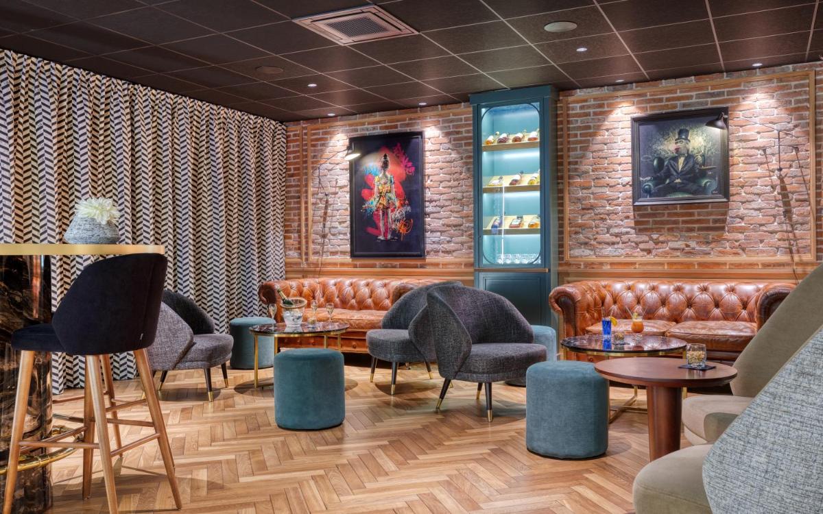 un restaurant avec des sièges et des tables en cuir et un mur en briques dans l'établissement Brit Hotel Les Voyageurs, à Loudéac